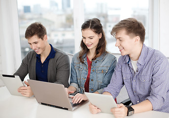 Image showing three smiling students with laptop and tablet pc