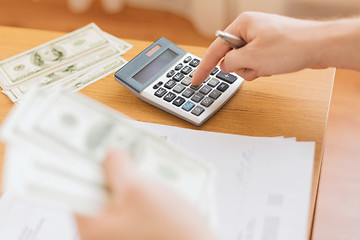 Image showing close up of man counting money and making notes