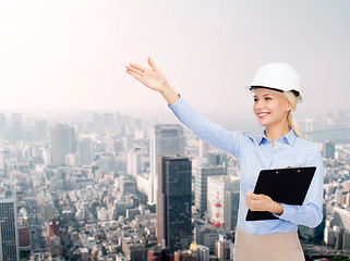 Image showing smiling businesswoman in helmet with clipboard