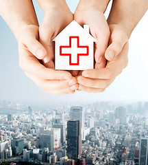 Image showing hands holding paper house with red cross