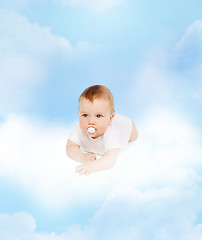 Image showing smiling baby lying on cloud with dummy in mouth