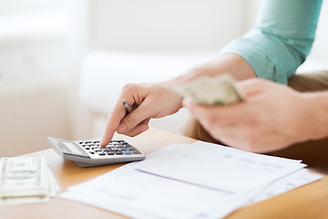 Image showing close up of man counting money and making notes