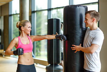 Image showing smiling woman with personal trainer boxing in gym