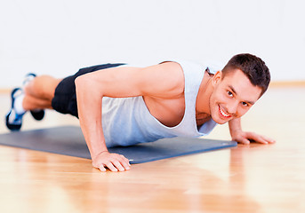 Image showing smiling man doing push-ups in the gym