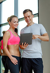 Image showing smiling young woman with personal trainer in gym