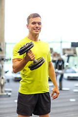 Image showing smiling man with dumbbell in gym