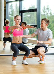 Image showing smiling woman with male trainer exercising in gym