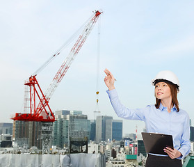 Image showing smiling businesswoman in helmet with clipboard