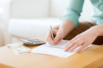 Image showing close up of man counting money and making notes