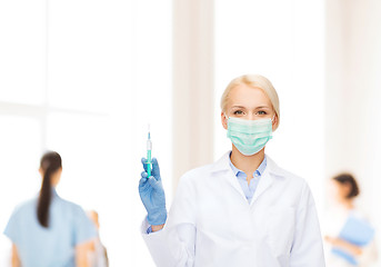 Image showing doctor in mask holding syringe with injection