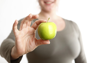 Image showing Woman holds a green apple into to camera