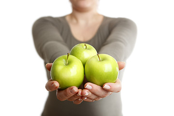 Image showing Woman holds three green apples into to camera