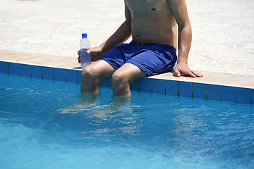 Image showing Attractive man with blue swimsuit and a bottle of water enjoys s