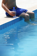 Image showing Attractive man with blue swimsuit and a bottle of water enjoys s