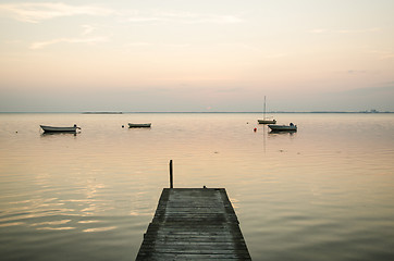 Image showing Old jetty with anchored rowing boats in the water