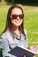 Image showing smiling young girl with book sitting in park