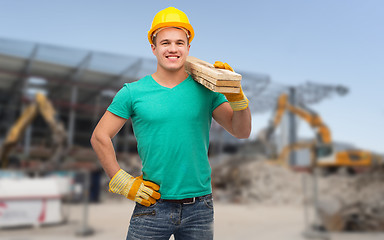 Image showing smiling manual worker in helmet with wooden boards