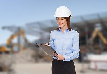 Image showing smiling businesswoman in helmet with clipboard