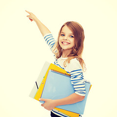 Image showing cute girl with folders pointing at virtual screen