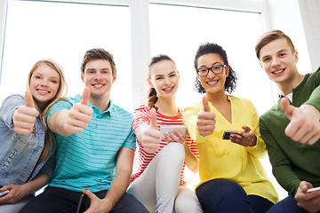 Image showing smiling students with smartphone texting at school