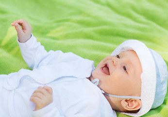 Image showing smiling baby lying on floor and looking up