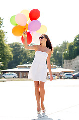 Image showing smiling young woman in sunglasses with balloons