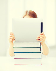 Image showing girl hiding behind tablet pc and books at school