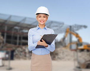 Image showing smiling businesswoman in helmet with clipboard