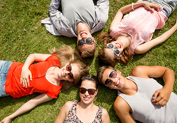 Image showing group of smiling friends lying on grass outdoors