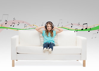 Image showing smiling little girl in headphones sitting on sofa
