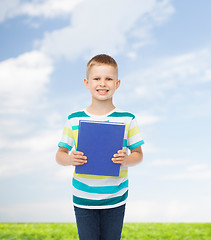 Image showing smiling little student boy with blue book