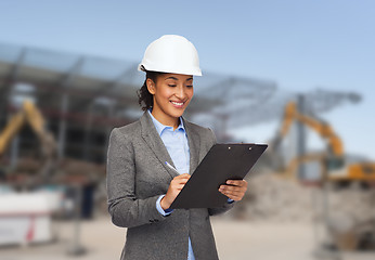 Image showing smiling businesswoman in helmet with clipboard