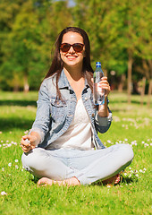 Image showing smiling young girl with bottle of water in park