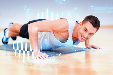 Image showing smiling man doing push-ups in the gym