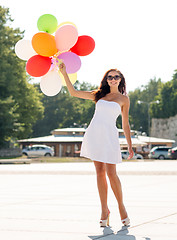 Image showing smiling young woman in sunglasses with balloons