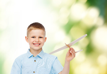 Image showing smiling little boy holding a wooden airplane model