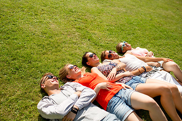 Image showing group of smiling friends lying on grass outdoors