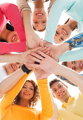 Image showing smiling teenagers with hands on top of each other