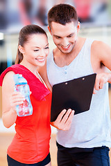 Image showing smiling male trainer with woman in the gym