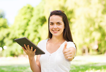 Image showing smiling young girl with tablet pc sitting on grass