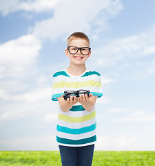 Image showing smiling boy in eyeglasses holding spectacles