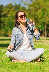 Image showing smiling young girl with bottle of water in park