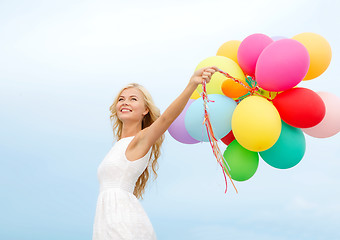 Image showing smiling woman with colorful balloons outside