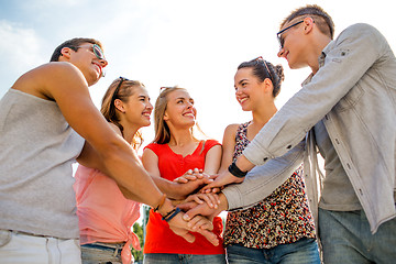 Image showing group of smiling friends with hands on top in city