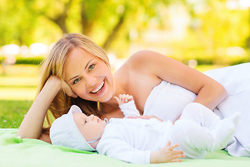 Image showing laughing mother lying with little baby on blanket