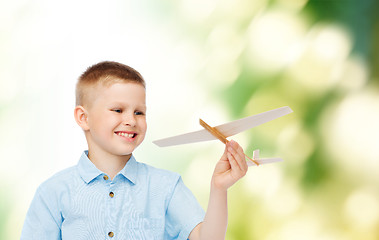 Image showing smiling little boy holding a wooden airplane model