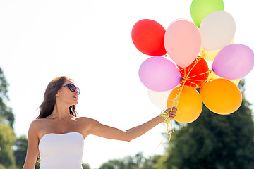 Image showing smiling young woman in sunglasses with balloons