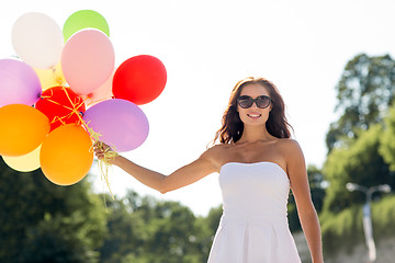 Image showing smiling young woman in sunglasses with balloons