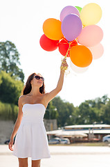 Image showing smiling young woman in sunglasses with balloons