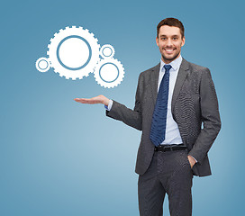 Image showing smiling businessman holding settings icon